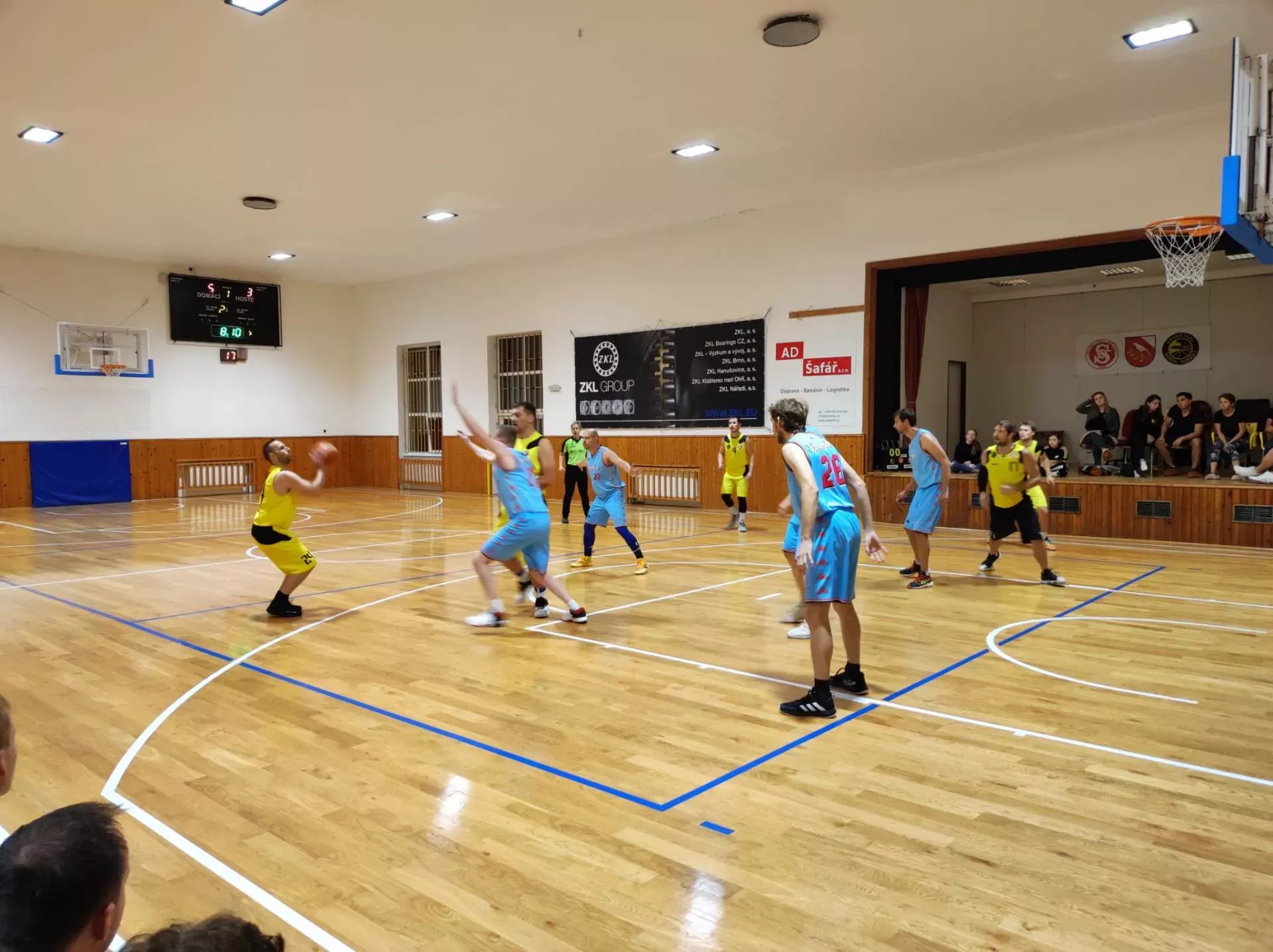 Muži B ve žlutých dresech v obraně proti soupeři ve světle modrých dresech
